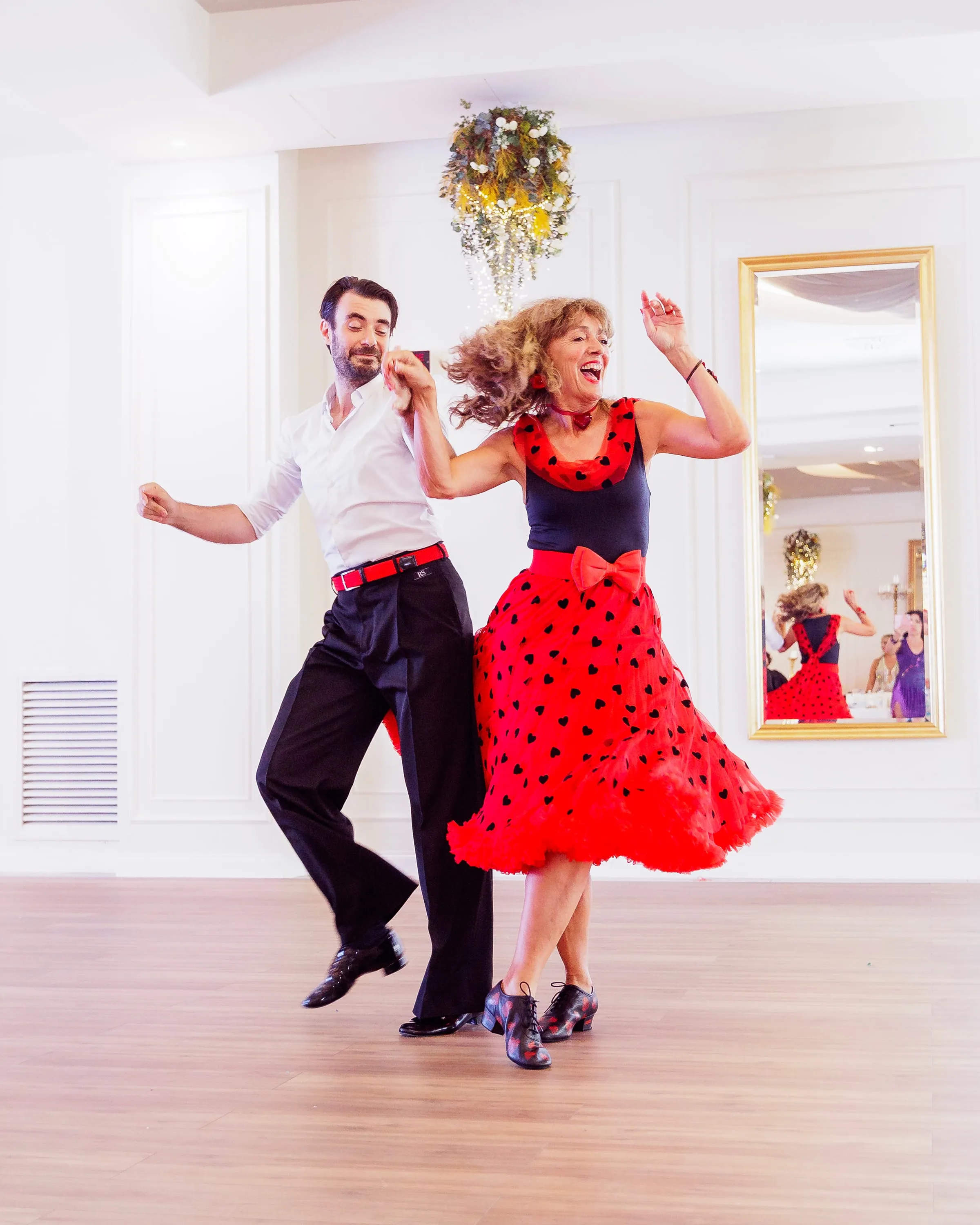 Zwei Tanzende springen in einer schwungvollen Boogie-Figur, rotes Kleid mit schwarzen Herzen.